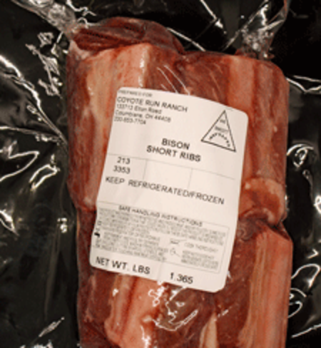 Bison short ribs packaged in vacuum seal with a label from Coyote Run Ranch, indicating safe handling instructions and storage recommendations.
