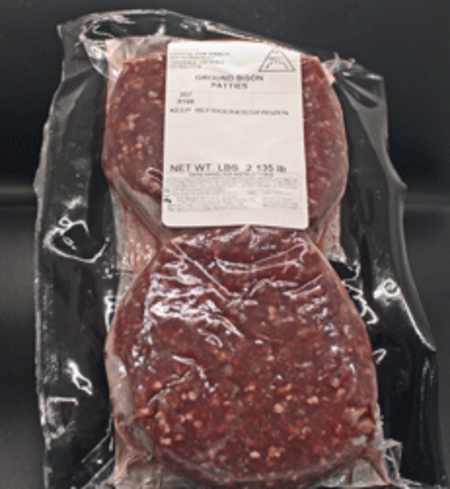Two vacuum-sealed ground bison patties in packaging, labeled with weight and storage instructions, on a dark background. Ideal for healthy meal preparation and grilling.
