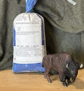 Bison seasoned sausage package with a toy bison figurine in front, placed on a wooden surface against a textured background.